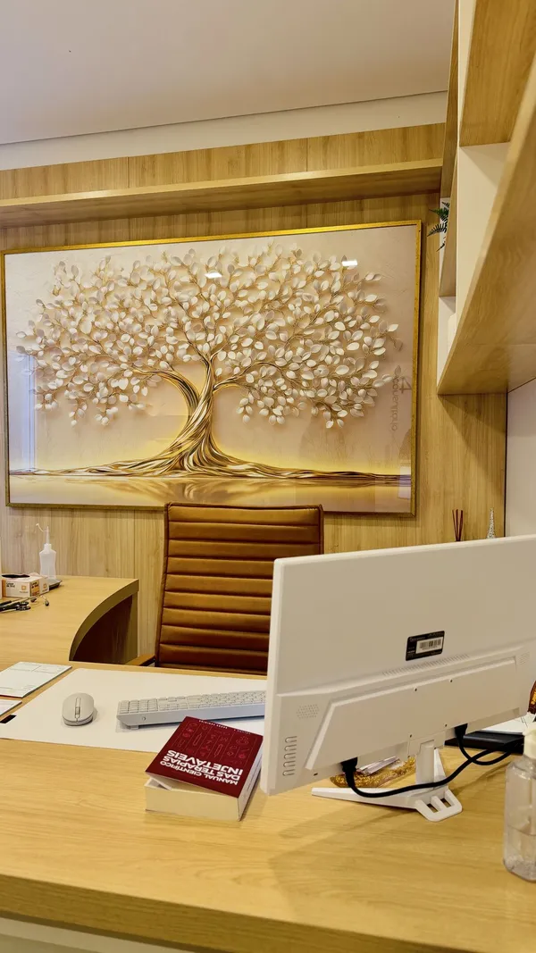 Quadro da árvore dourada, símbolo da Dra. Franciele, atrás da mesa de atendimento do consultório em Santiago, RS