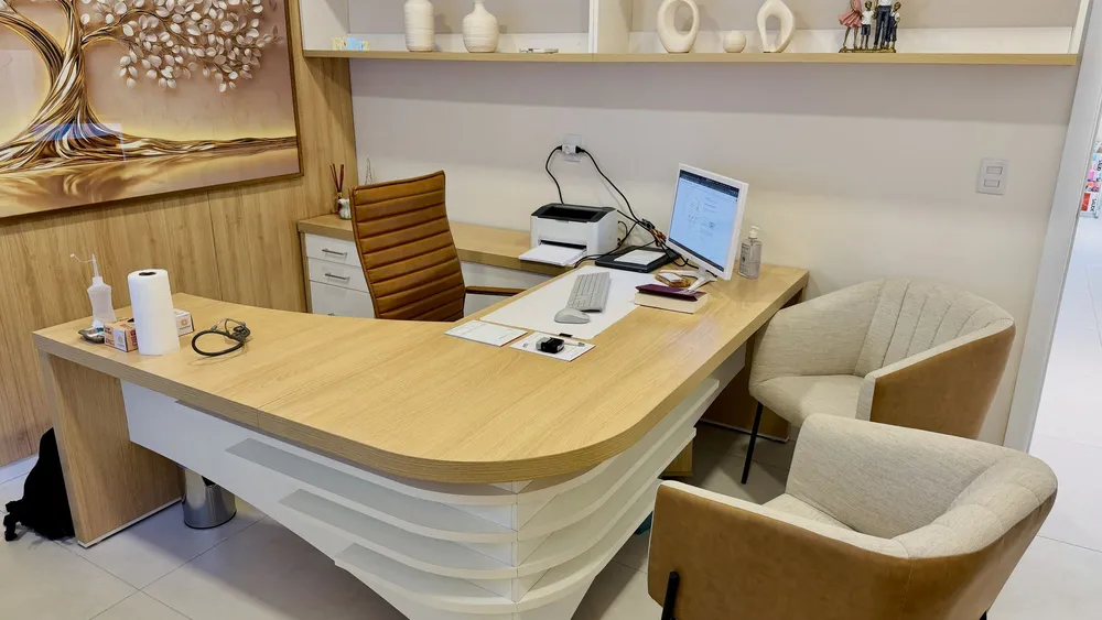 Sala de atendimento do consultório de oncologia da Dra. Franciele Spode em Santiago, RS, com mesa e poltronas para paciente e acompanhante